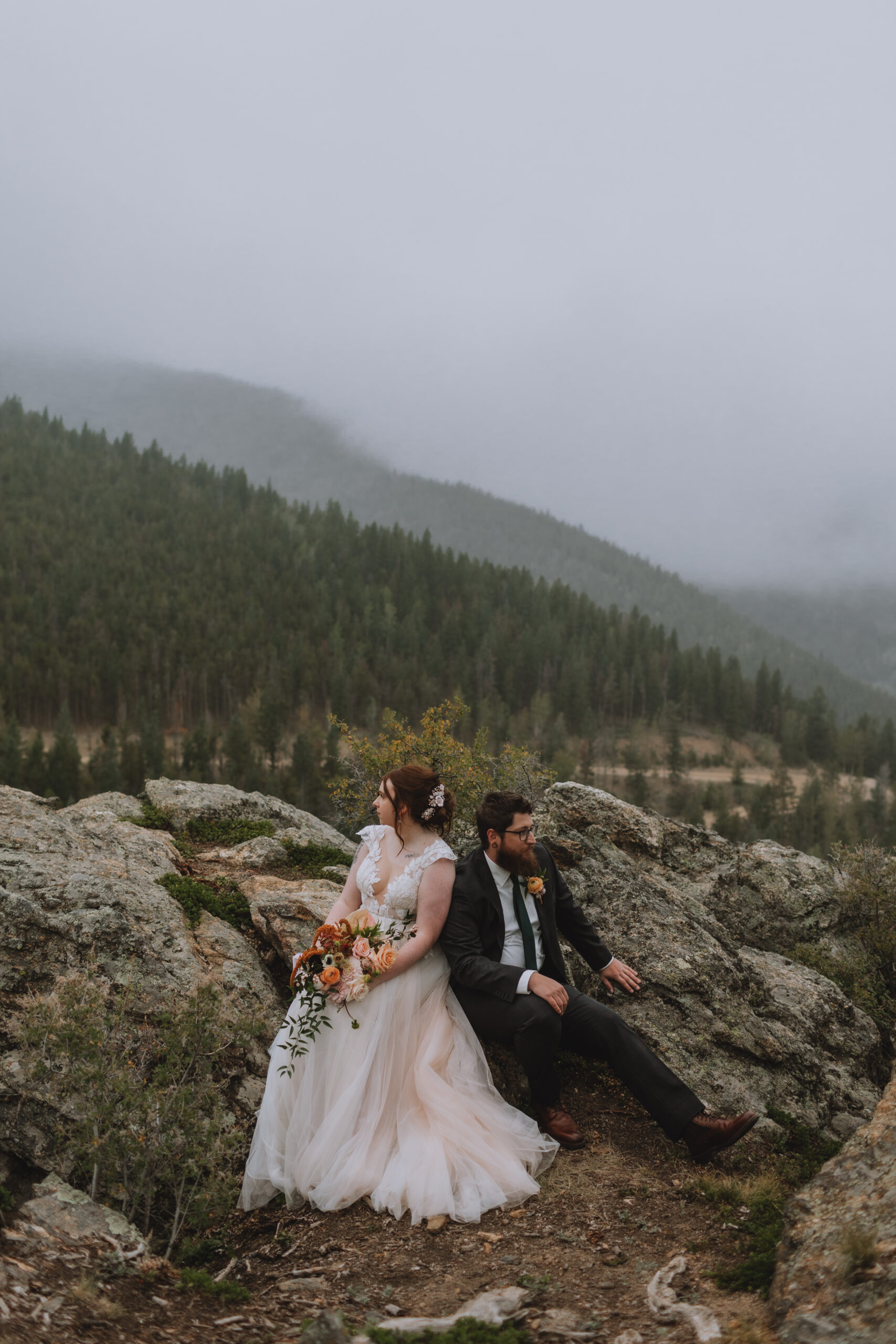 Bride and groom sitting on a rock