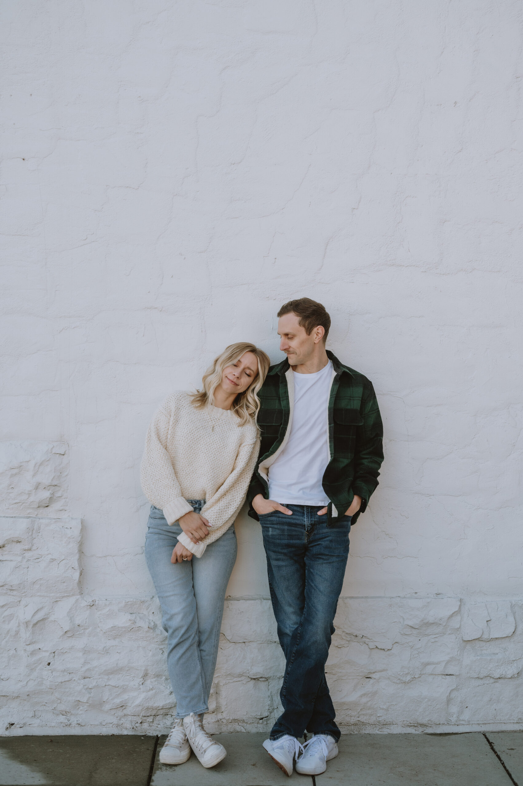 engaged couple leaning on a brick wall